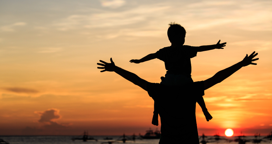 A father and son watching a sunset from the beach